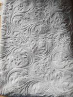 Folded white cotton bath sheet displaying embossed floral swirl texture