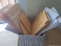 Open box showing mix of tan and white envelopes in varying sizes