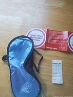 Blue satin eye mask, red seat hanger sign, leaflet on table