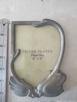 Front view of silver-plated frame with 4" x 6" placeholder and attached ruler for scale