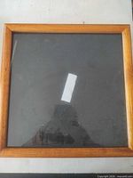 Front view of square wood frame with glass and black interior