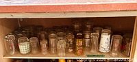 First shelf with multiple small tumblers and novelty printed glasses