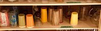 Upper shelf showing colored plastic tumblers, assorted glasses, and glass pitcher