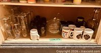 Full shelf showing glassware, jars, mugs and carafe