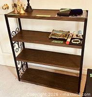 Full view of shelving unit showing four shelves and metal scroll side