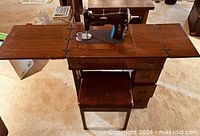 Sewing machine in opened cabinet with stool and side panels extended