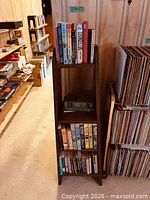 Full view of slender wooden bookcase with three shelves filled with books