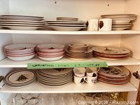 Multiple stacks of dinner, salad plates and mugs on upper shelf