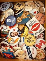 Box filled with assorted round pin-back buttons showing various slogans and graphics