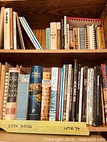 Two wooden shelves filled with assorted cookbooks, full lot view
