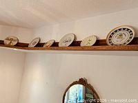 Row of decorative plates on shelf, assorted motifs