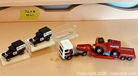 Overview showing two black trucks in cases plus semi with trailer and tractor