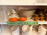 Full shelf showing plates, saucers, glasses, mugs, egg cups, gravy boat
