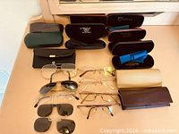 Overview of eyeglasses, sunglasses and multiple cases on tabletop