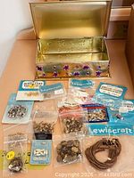 Open tin showing all sealed packs of jewellery findings and cord