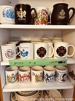 Three shelves of assorted commemorative mugs