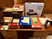 Overall view of office supplies on table including LapDesk, trays, file boxes, folders, labels, envelopes, Post-its and tape