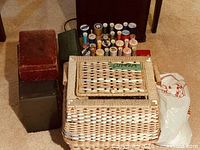 Overall lot showing wicker sewing basket, thread spools, green Singer case, red and grey boxes