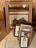 Stacked group of frames leaning against wall showing variety of sizes and finishes