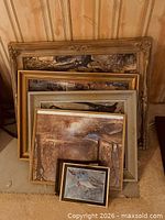 Stack of six assorted picture frames leaning against wall
