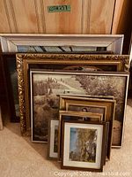 Stack of framed pictures and frames in various sizes and finishes