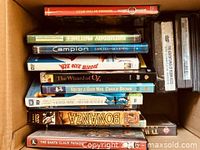 Stack of mixed DVDs in box showing several titles