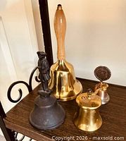 Four assorted metal bells displayed on shelf