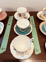 Three teacup and saucer sets arranged between green tape markers