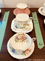 Three bone china teacup and saucer sets displayed on table