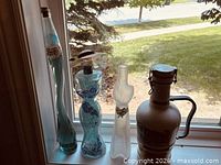 All four decorative bottles lined on windowsill