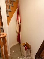 Full-size Canadian flag on pole leaning against wall near stairs
