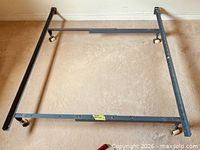 Full view of assembled metal bed frame showing rails, crossbar and casters