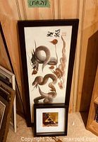 Both framed artworks leaning against wall
