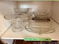 overview of clear pressed glass trays and bowls on shelf