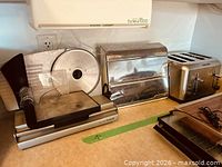All three items on countertop: food slicer, chrome dispenser, stainless toaster