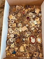 Box filled with mixed gold-tone jewelry pieces