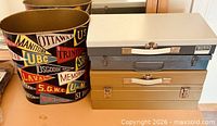Wastebasket with pennant graphics beside stacked slide cases