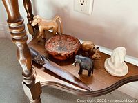 All six items grouped on shelf: monkey, bowl, letter opener, elephant, hippo, stone lion