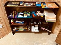 Front view of dark stained wooden bookcase filled with miscellaneous items