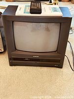 Front view of Samsung CRT TV-VCR combo with remote and book on top