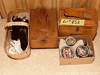 two wooden shoe shine boxes, basket of brushes, cardboard box of polish tins