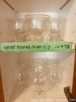 Two rows of clear glass shrimp dishes inside cabinet