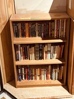 Full view of small wooden bookcase with three levels of books