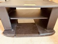 Front view of black TV stand showing shelves and curved base