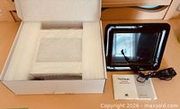 Digital frame, adapter and manual beside open protective box