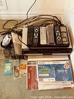 Full lot showing stacked electronics, remotes, discs, cables and manuals