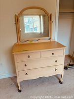 Full view of dresser showing four drawers, attached mirror, legs with casters