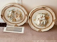 Both oval chalkware plaques side by side on floor