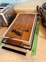 Two stacked electric warming trays showing size and surface materials
