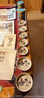 Row of eight cream ceramic dishes with Egyptian scenes on tabletop